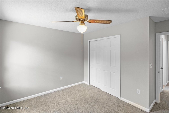 unfurnished bedroom with a textured ceiling, ceiling fan, carpet, and a closet