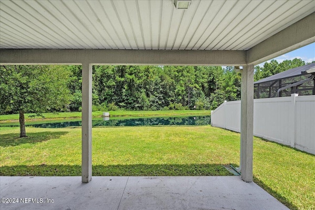 view of yard with a patio area, glass enclosure, and a water view