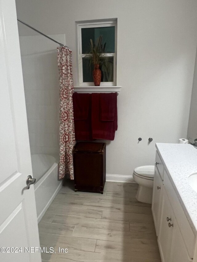 full bathroom with shower / bath combo with shower curtain, wood-type flooring, toilet, and vanity