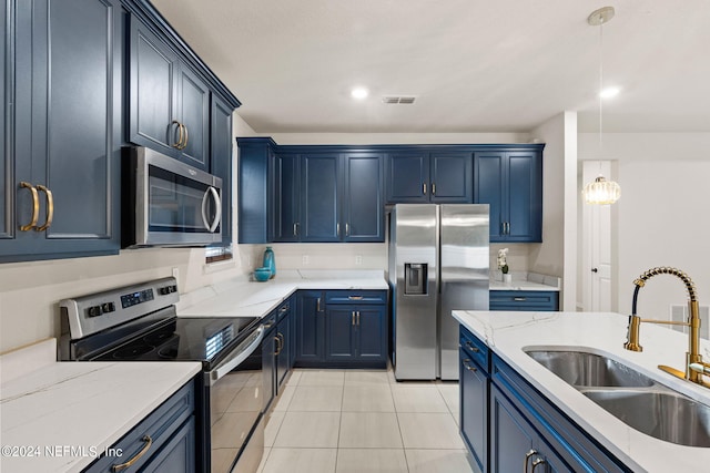 kitchen featuring blue cabinetry, light tile patterned flooring, sink, pendant lighting, and stainless steel appliances