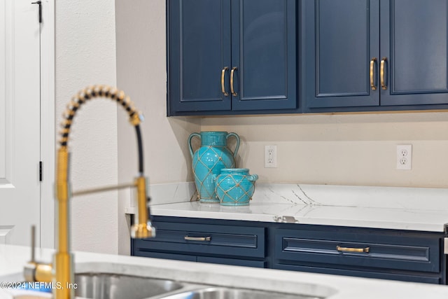 room details featuring blue cabinetry and light stone counters