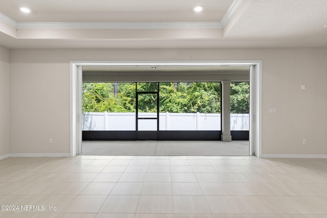 tiled empty room featuring crown molding, plenty of natural light, a tray ceiling, and a textured ceiling