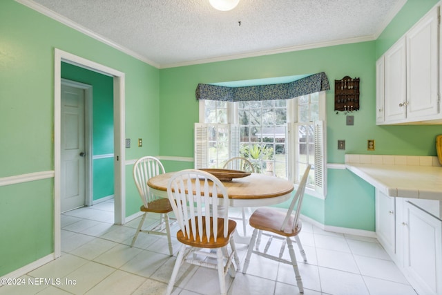 tiled dining room with ornamental molding and a textured ceiling