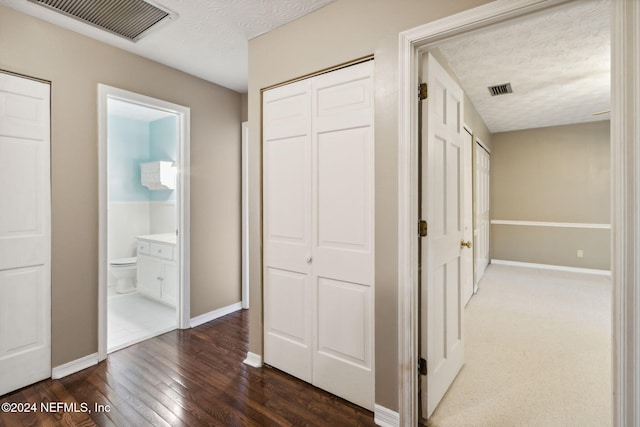 hall with a textured ceiling and dark hardwood / wood-style floors