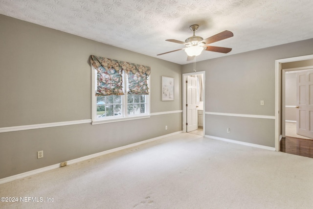 unfurnished bedroom featuring light carpet, a textured ceiling, and ceiling fan