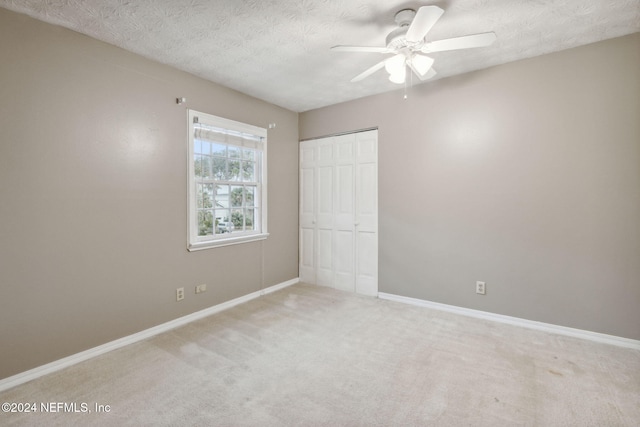 unfurnished bedroom with ceiling fan, carpet floors, a textured ceiling, and a closet