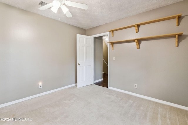 carpeted spare room with ceiling fan and a textured ceiling