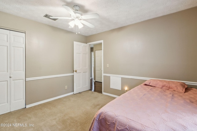 carpeted bedroom featuring ceiling fan, a textured ceiling, and a closet