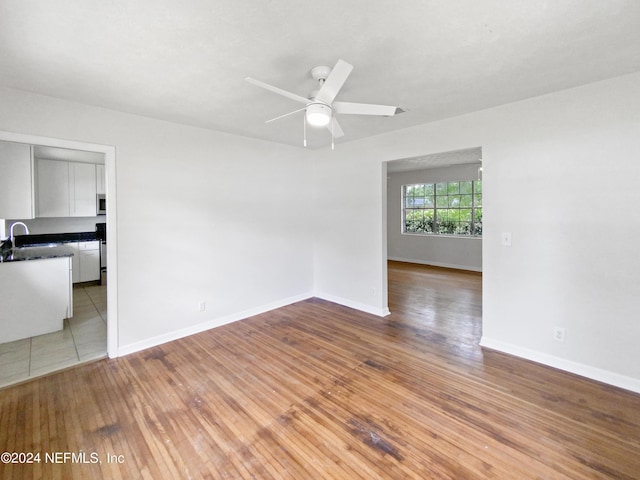 spare room with ceiling fan, sink, and light wood-type flooring