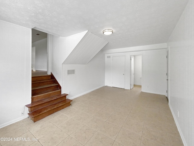 additional living space with a textured ceiling and light tile patterned flooring