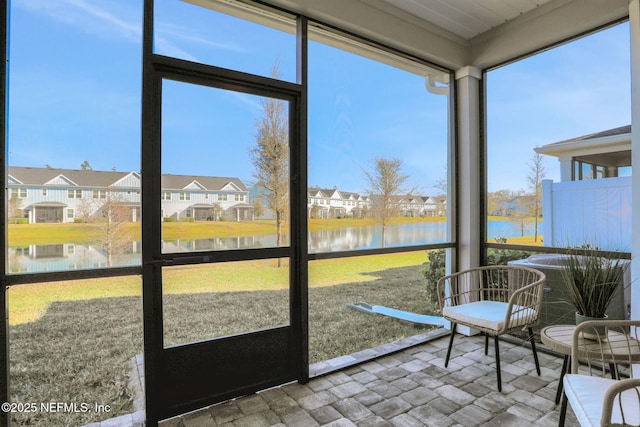 sunroom / solarium with plenty of natural light, a water view, and a residential view