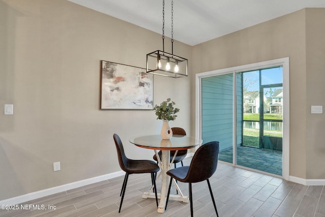 dining space with baseboards, a notable chandelier, and wood tiled floor