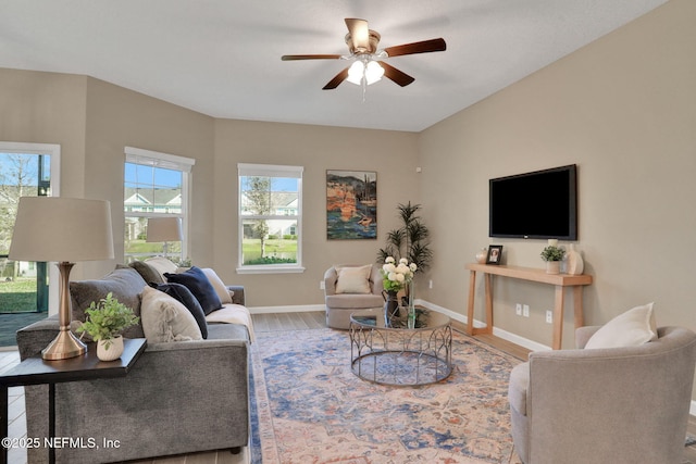 living area with plenty of natural light, baseboards, a ceiling fan, and wood finished floors