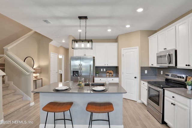 kitchen with a kitchen breakfast bar, visible vents, appliances with stainless steel finishes, and wood finish floors