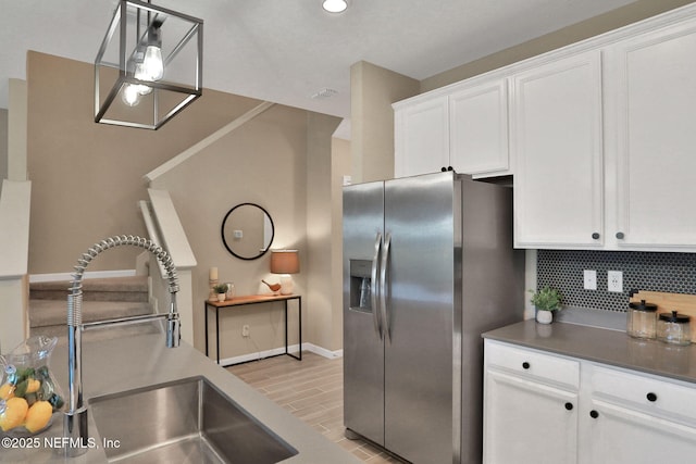 kitchen featuring white cabinetry, tasteful backsplash, stainless steel refrigerator with ice dispenser, and a sink