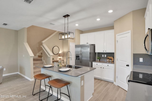 kitchen featuring a sink, backsplash, appliances with stainless steel finishes, and wood finish floors