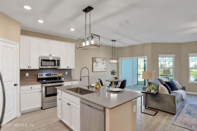 kitchen featuring a healthy amount of sunlight, open floor plan, decorative backsplash, appliances with stainless steel finishes, and a sink