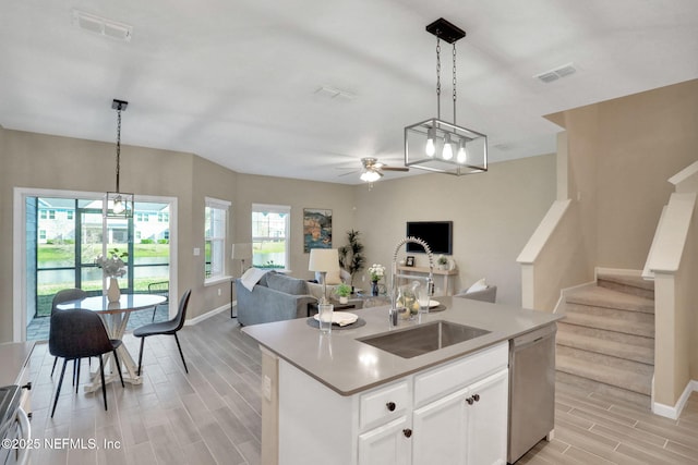 kitchen with a ceiling fan, visible vents, wood finish floors, a sink, and stainless steel dishwasher