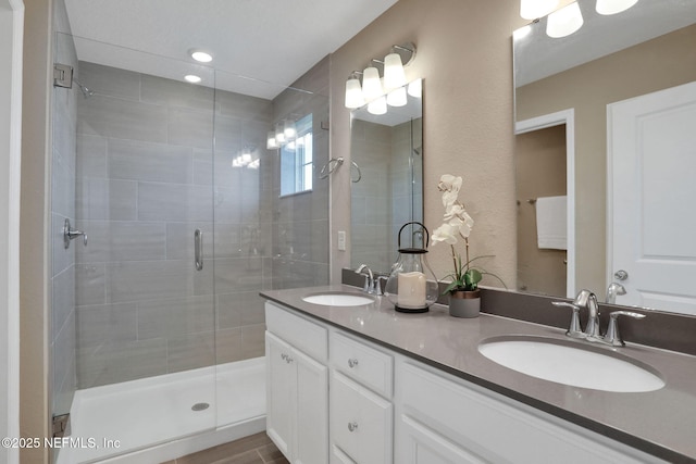 bathroom with a shower stall, double vanity, and a sink