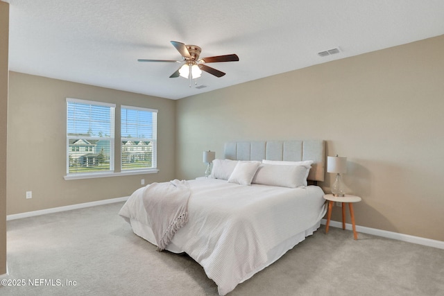 bedroom featuring a ceiling fan, baseboards, visible vents, a textured ceiling, and light carpet