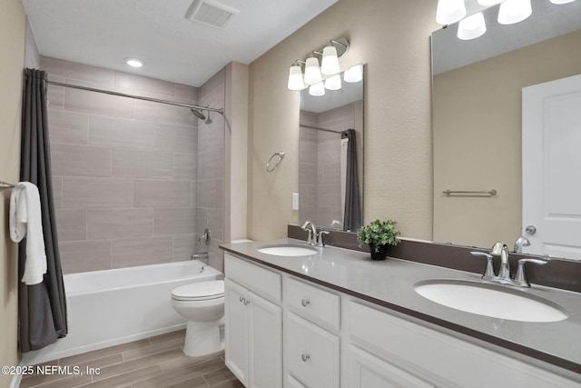 full bath featuring wood finish floors, toilet, visible vents, and a sink