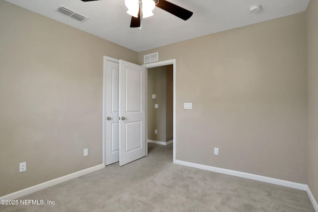 carpeted spare room featuring visible vents, baseboards, and a ceiling fan