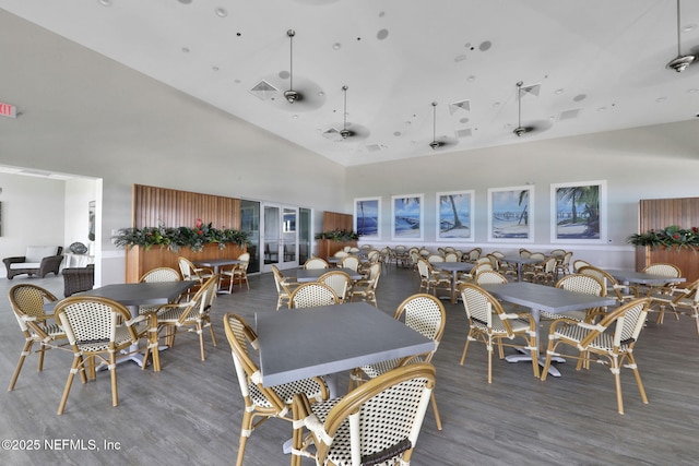 dining area featuring wood finished floors, visible vents, and high vaulted ceiling