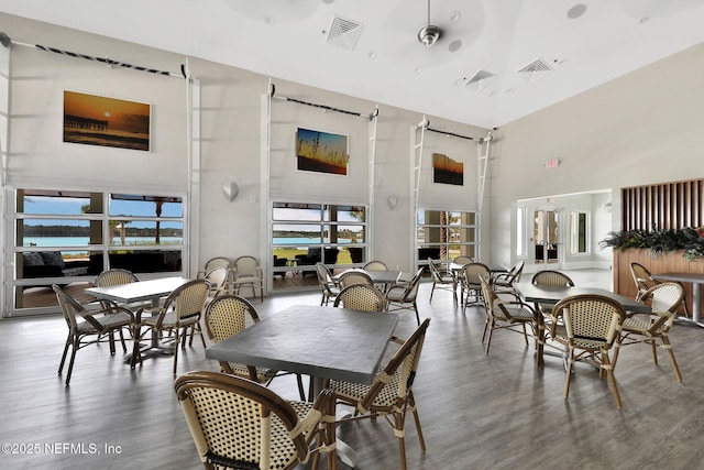 dining space with visible vents, a high ceiling, and wood finished floors