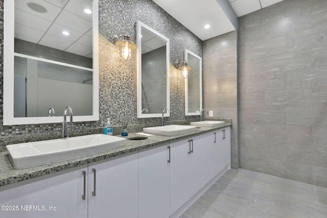 bathroom with tile walls, double vanity, and a sink