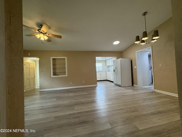 unfurnished living room with ceiling fan with notable chandelier, lofted ceiling, and light wood-type flooring