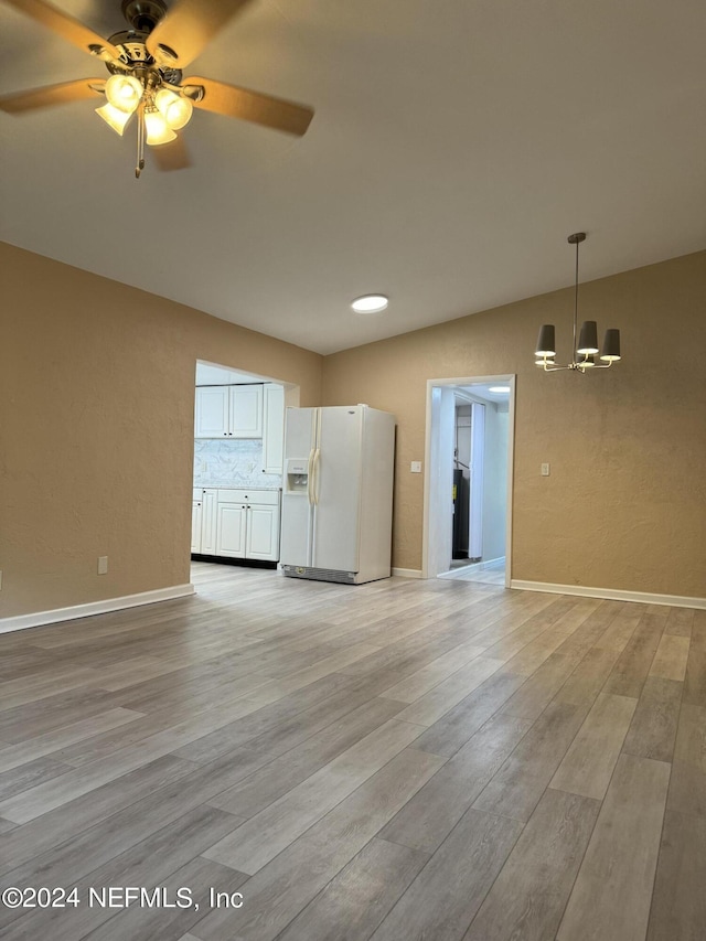 unfurnished living room with ceiling fan with notable chandelier, light hardwood / wood-style flooring, and lofted ceiling