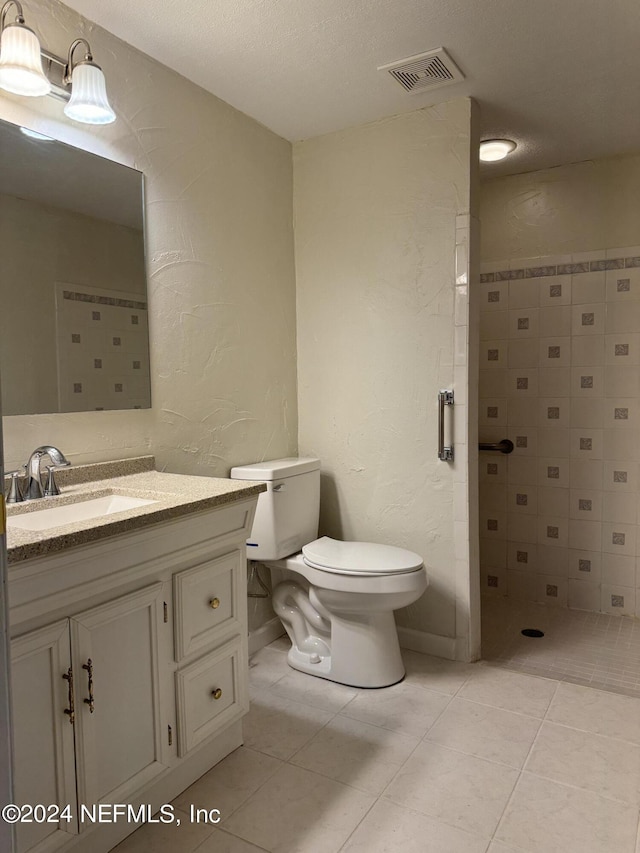 bathroom featuring toilet, vanity, tile patterned floors, and a textured ceiling