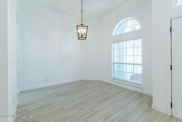 unfurnished dining area featuring a notable chandelier and light hardwood / wood-style flooring