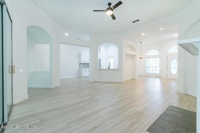 unfurnished living room featuring lofted ceiling, sink, light hardwood / wood-style floors, and ceiling fan