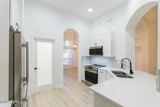 kitchen with sink, white cabinets, pendant lighting, stainless steel appliances, and backsplash