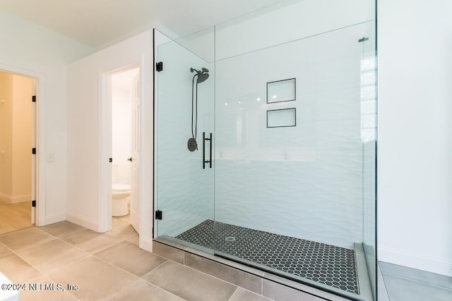 bathroom with an enclosed shower, tile patterned floors, and toilet