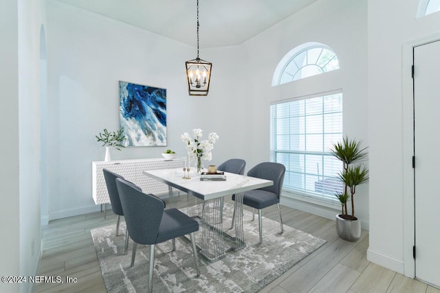 dining space with a notable chandelier, a wealth of natural light, and light wood-type flooring