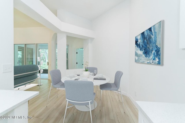 dining space with a high ceiling and light hardwood / wood-style flooring