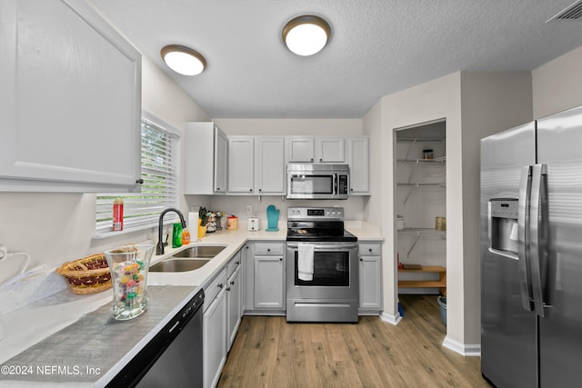 kitchen featuring stainless steel appliances, a sink, visible vents, light countertops, and light wood-type flooring