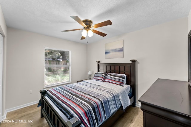 bedroom featuring a textured ceiling, baseboards, and light wood-style floors