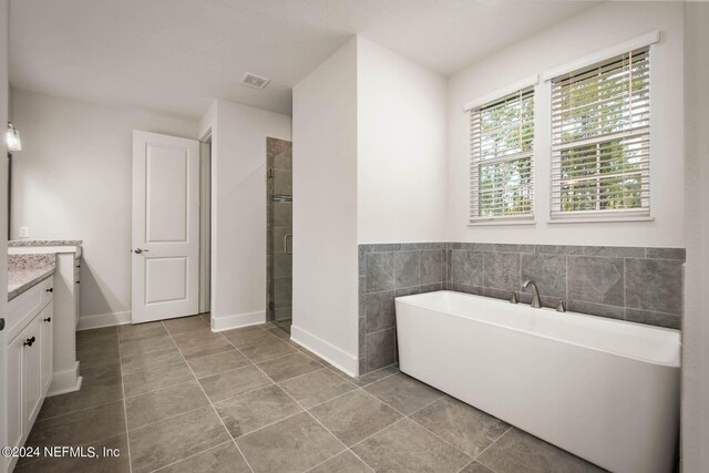 36247 Pitch Ln, Hilliard, FL 32046 - bathroom with tile patterned flooring, vanity, visible vents, a soaking tub, and a stall shower