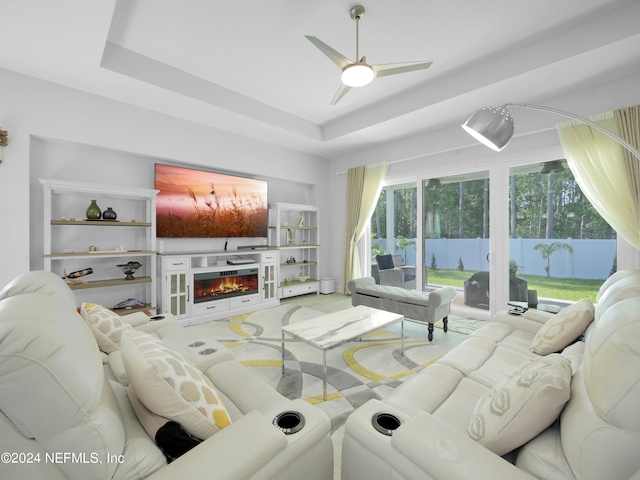 living room featuring a tray ceiling, ceiling fan, and carpet