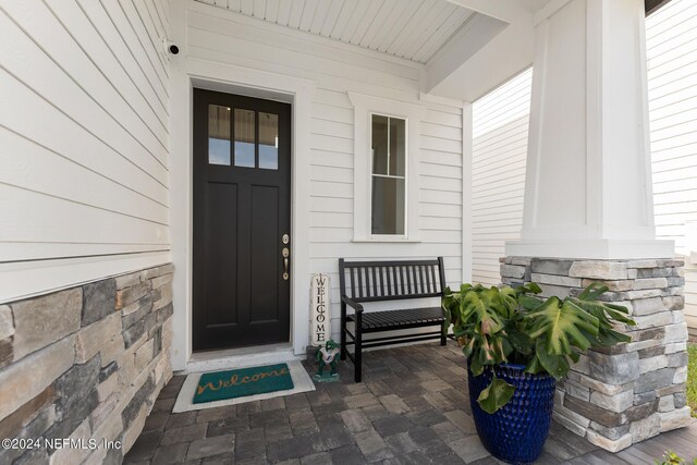 entrance to property featuring stone siding and a porch