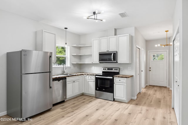 kitchen with sink, appliances with stainless steel finishes, white cabinetry, light hardwood / wood-style floors, and decorative light fixtures