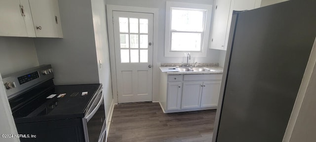 kitchen with stainless steel appliances, sink, hardwood / wood-style floors, and white cabinets