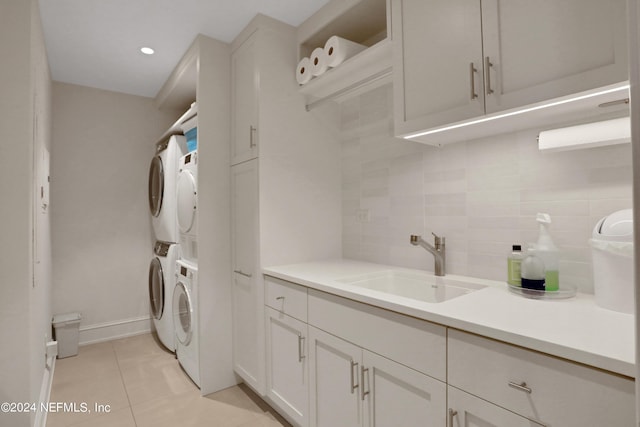 laundry area featuring stacked washer and clothes dryer, sink, and light tile patterned floors