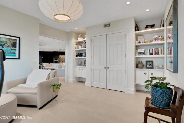 living area featuring built in shelves and light colored carpet