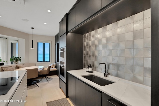 kitchen with light stone counters, sink, hanging light fixtures, and light tile patterned floors