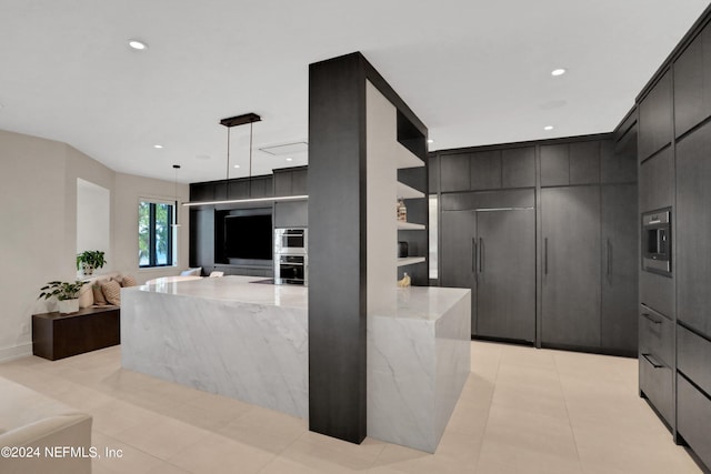 kitchen with light stone counters, double oven, hanging light fixtures, and light tile patterned floors