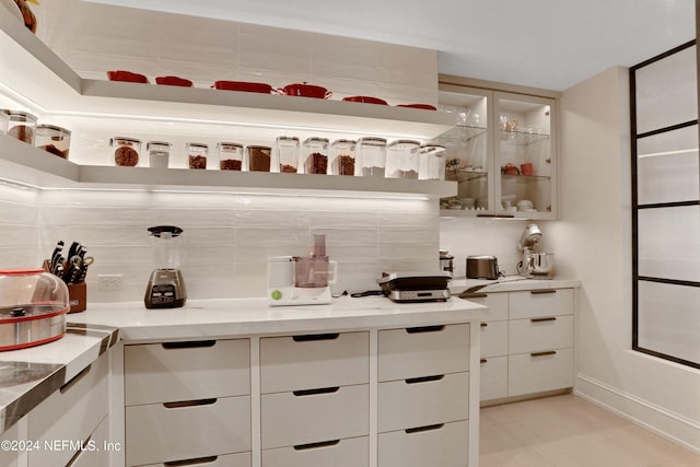 bar featuring light stone counters, white cabinets, light tile patterned floors, and backsplash